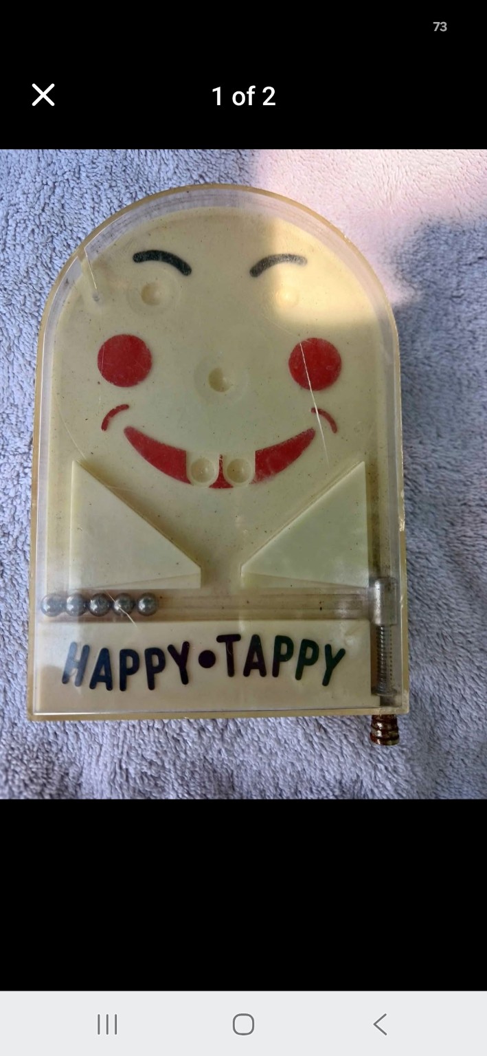 Vintage Happy Tappy tabletop pinball toy with a smiling face.